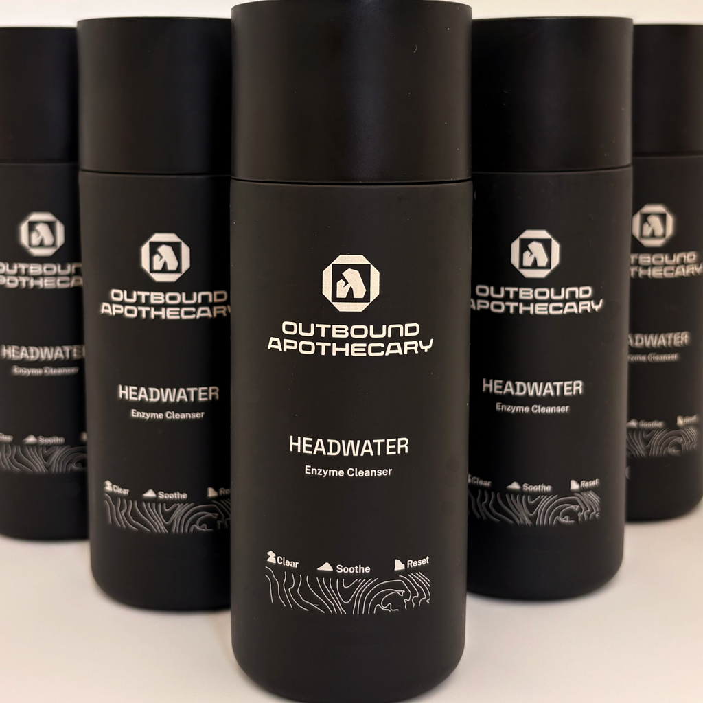 Black bottles of Outbound Apothecary Headwater Enzyme Cleanser on a white background