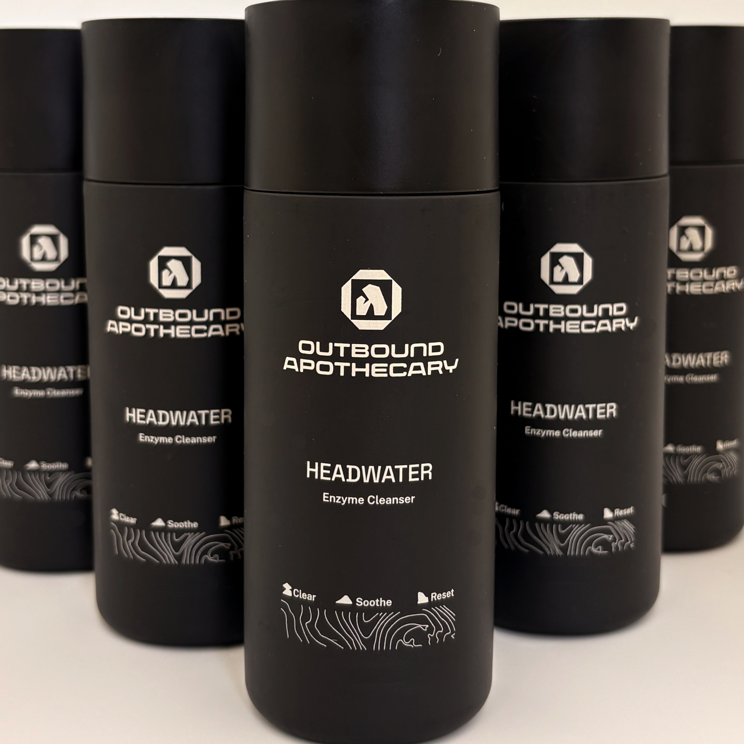 Black bottles of Outbound Apothecary Headwater Enzyme Cleanser on a white background